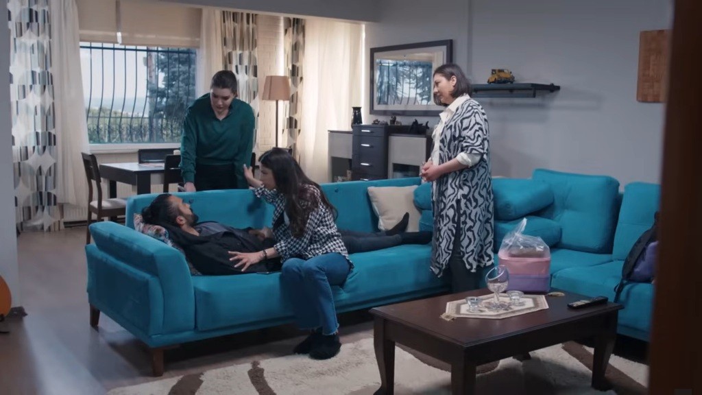 Scena w domu Ayse. Ferit leży na kanapie.