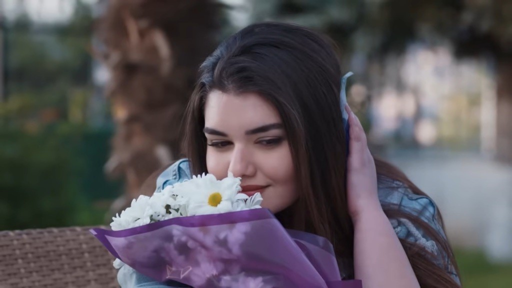 Nese napawa się zapachem kwiatów. Drugą ręką przykłada torebkę z lodem do głowy, w miejsce, gdzie została uderzona.