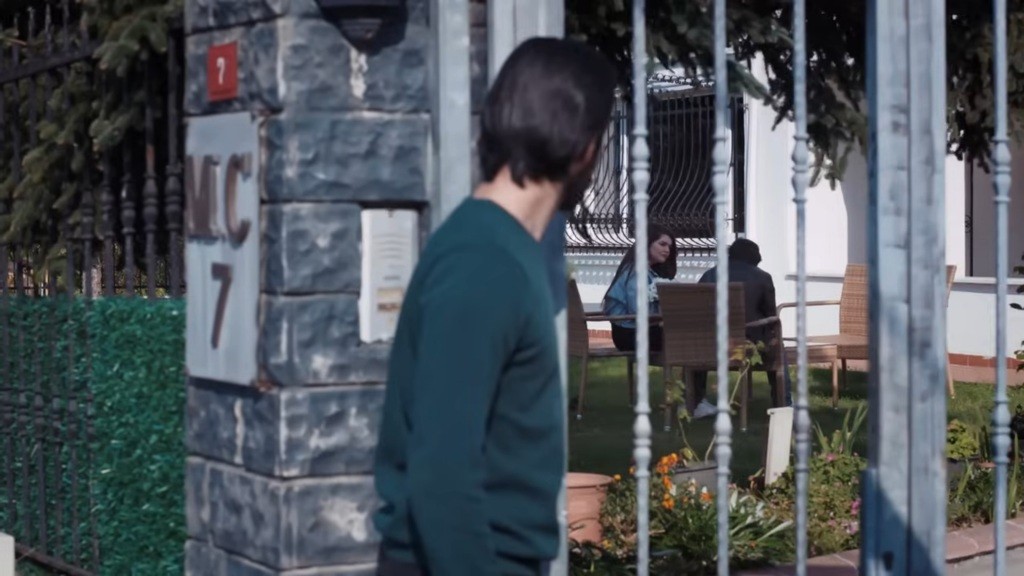 Volkan zatrzymał się przed bramą i patrzy na rozmawiających w ogrodzie Nese i towarzyszącego jej mężczyznę.