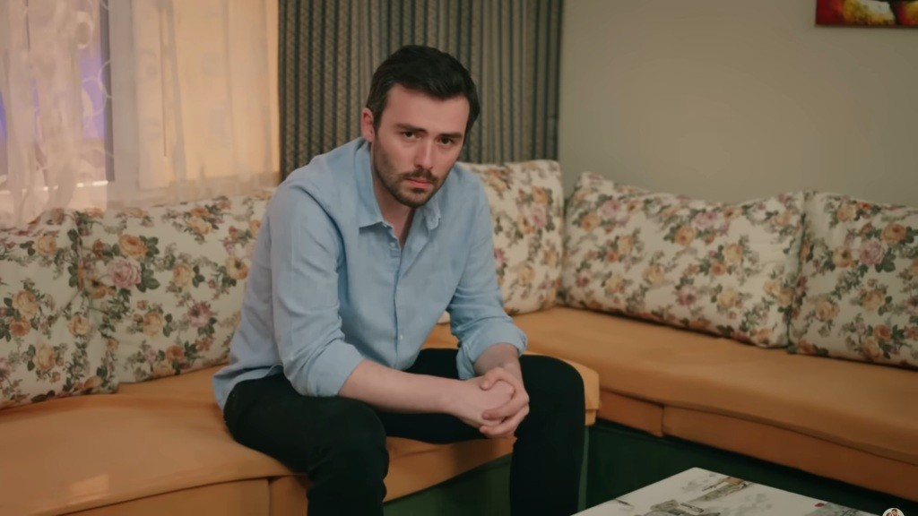 Pogrążony w zadumie Hakan siedzi na sofie.