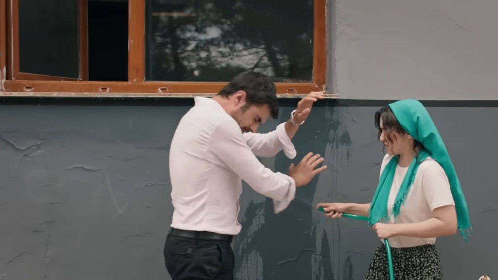 Zeynep oblewa Halila wodą z węża ogrodowego.