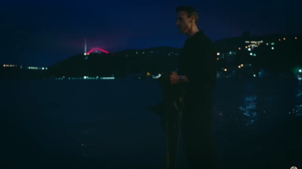 Alper stoi nocą nad klifem.