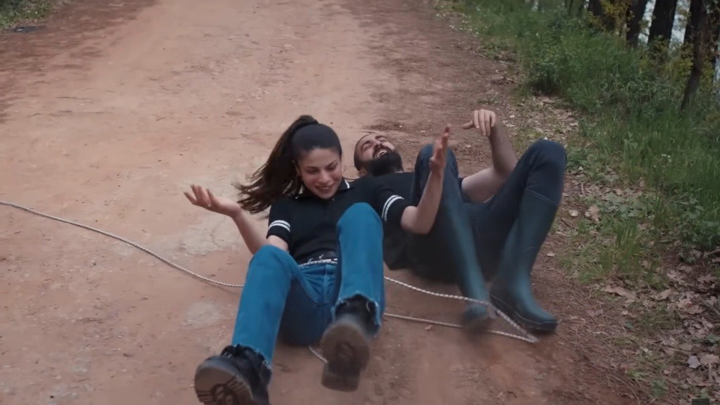 Ayse i Ferit leżą na drodze gruntowej, bawiąc się jak dzieci.