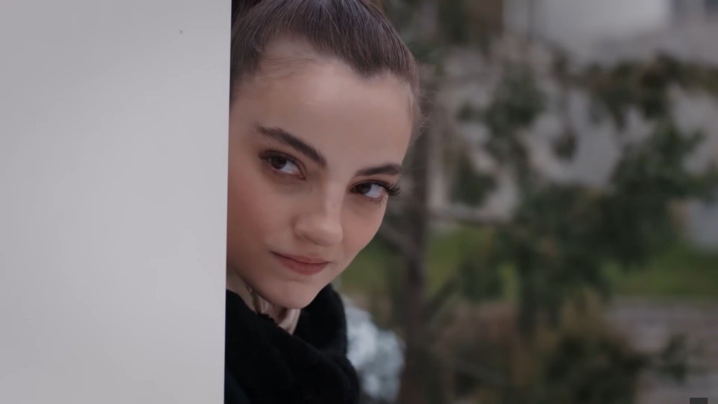 Basak uśmiecha się cwaniacko, wyglądając zza winkla.