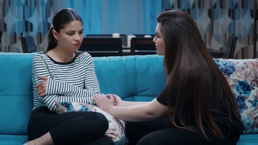 Ayse i Nese rozmawiają na kanapie. Nese ujmuje rękę siostry, okazując jej wsparcie.