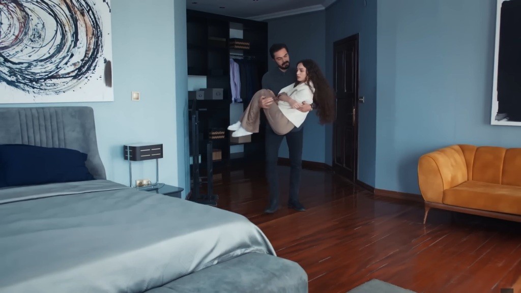Yaman niesie Nanę na rękach w sypialni.