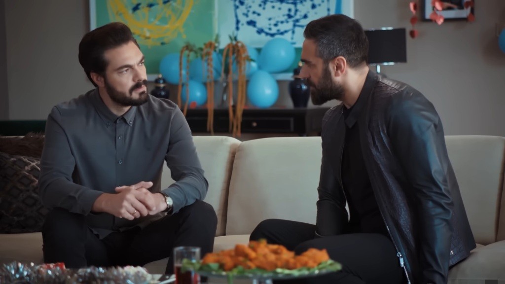 Yaman i Acar siedzą na kanapie w salonie.