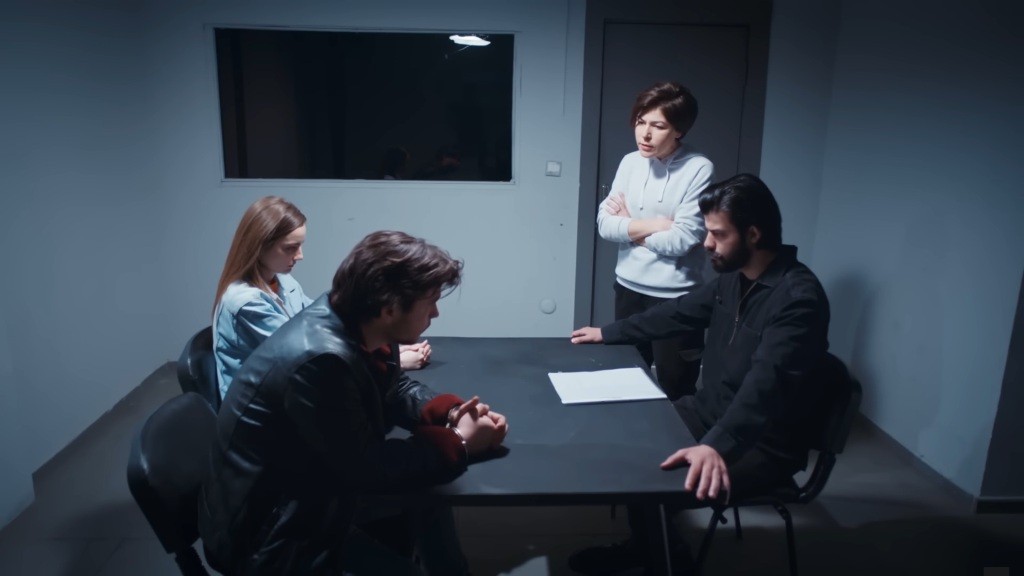 Scena w pokoju przesłuchań. Volkan siedzi przy stoliku, naprzeciwko zatrzymanych Basak i jej wspólnika. Obok stoi Kara.