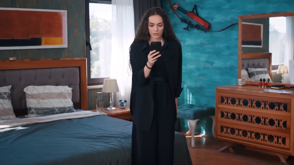 Nana stoi na środku pokoju, wpatrując się w ekran telefonu. Jest zszokowana.