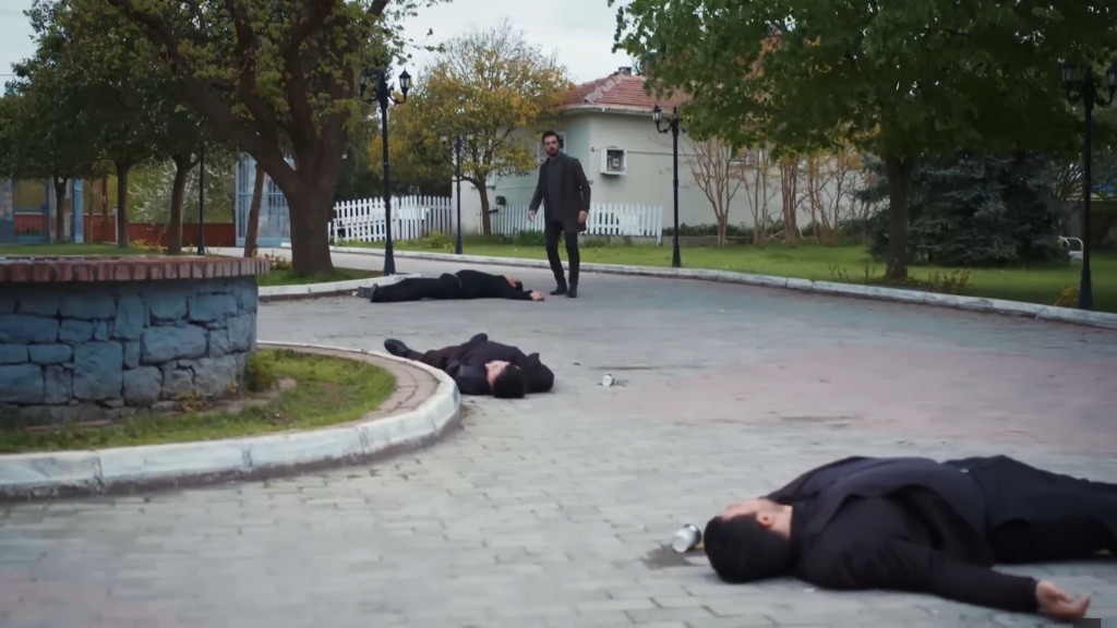 Na podwórku leżą nieprzytomni ochroniarze. Yaman idzie stoi obok jednego z nich.