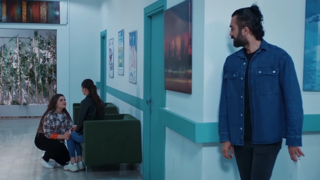 Ferit wygląda zza rogu ściany, przysłuchując się rozmowie Nese i Ayse.