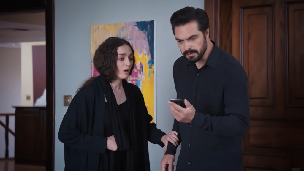 Yaman trzyma telefon w ręku. Obok niego stoi Nana. Oboje są zszokowani.