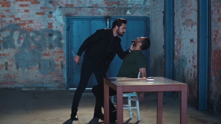 Trucizna zostaje więźniem Yamana. Jest przywiązany do krzesła, a Yaman trzyma go za szczękę.