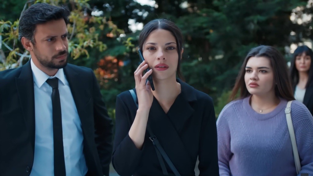 Ayse odbiera telefon. Obok niej stoją Koray i Nese.