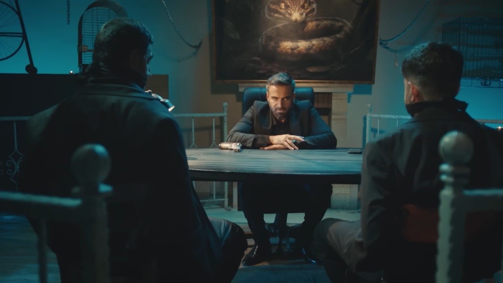 Trucizna wpatruje się w dwójch przywiązanych do krzeseł mężczyzn.