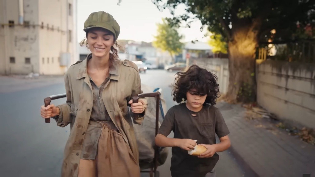 Nana i Yusuf idą ulicą. Nana ciągnie za sobą wózek.