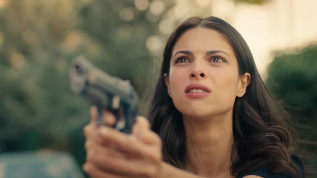 Ayse ściska pistolet w rękach. Jej oczy płoną determinacją.
