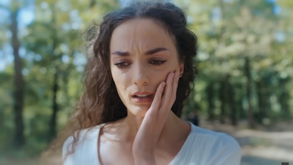 Nana dotyka się policzka.