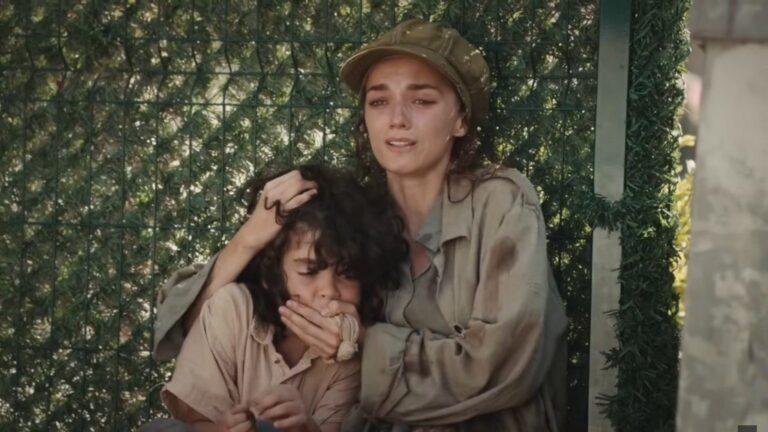 Nana i Yusuf ukrywają się za żywopłotem.