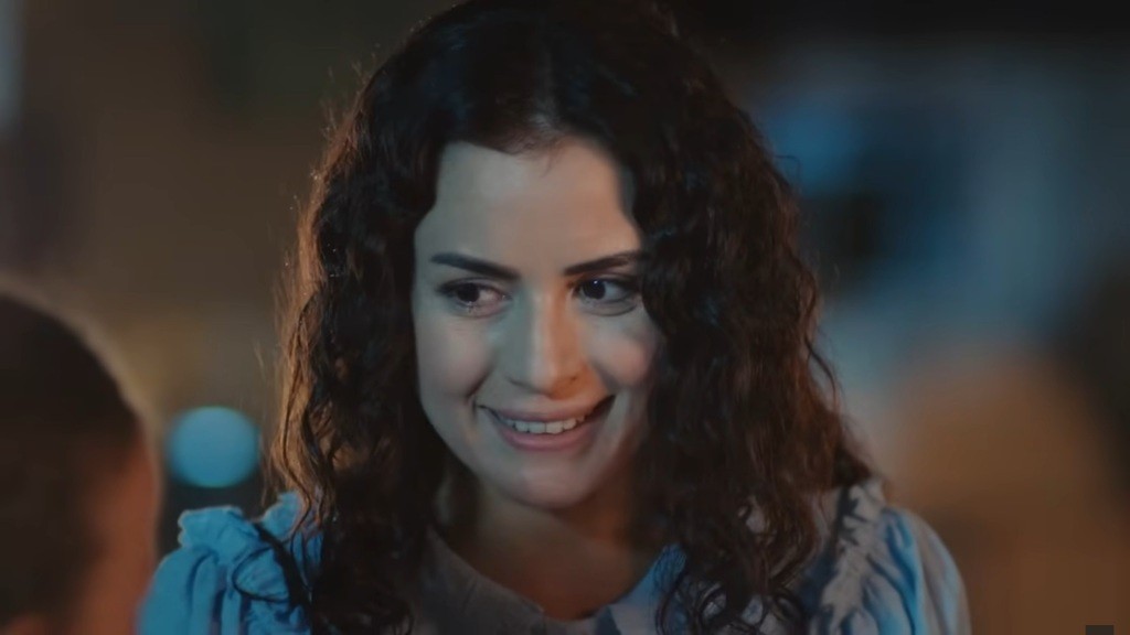 Aynur uśmiecha się, rozmawiając z Dogą.