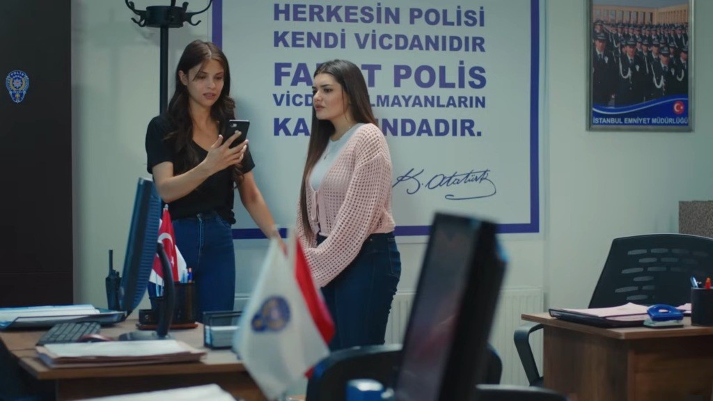 Ayse trzyma telefon w ręku. Obok niej stoi Nese.