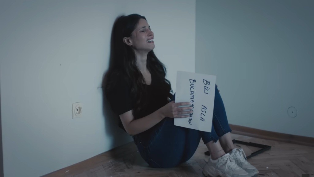 Ayse jest zrozpaczona. Siedzi pod ścianą, trzymając w ręku zdjęcie, na rewersie którego znajduje się napis: "Nigdy nas nie znajdziesz".