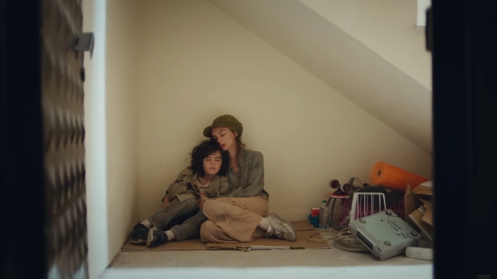 Yusuf i Nana śpią, siedząc pod ścianą, przytuleni.