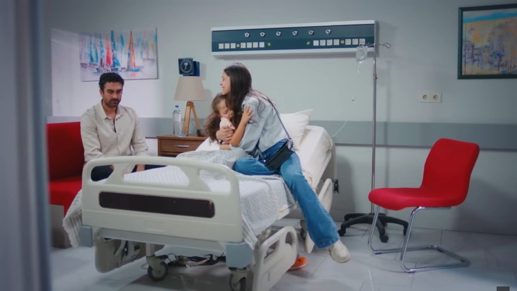 Ayse przytula córkę. Siedzący obok Ferit spuszcza głowę.