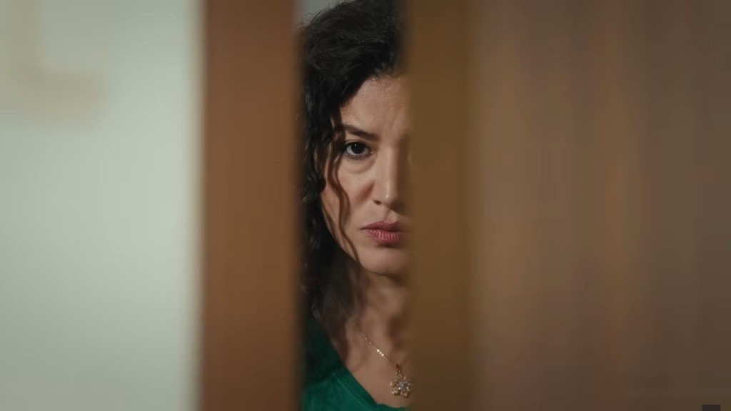 Cansel, bratowa Poyraza, stoi przy uchylonych drzwiach. Jej twarz zdradza napięcie.