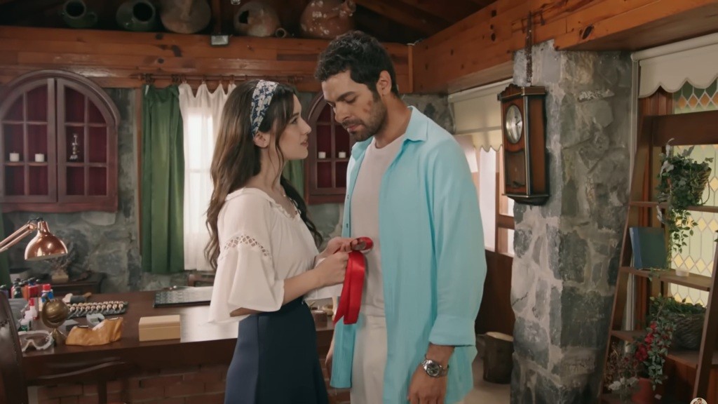 Zeynep i Halil w pracowni. Zeynep trzyma w rękach czerwoną wstążkę.