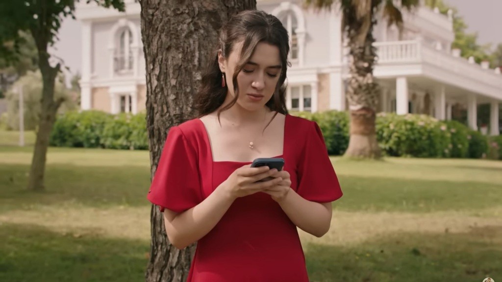 Zeynep znajduje się w ogrodzie i wpatruje się w telefon.
