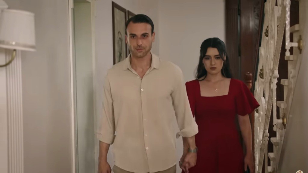Alper prowadzi Zeynep przez hol, trzymając ją za rękę.