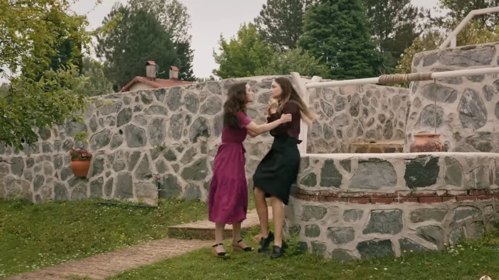 Zeynep chwyta Asu za ramiona, popychając ją na kamienny mur studni.
