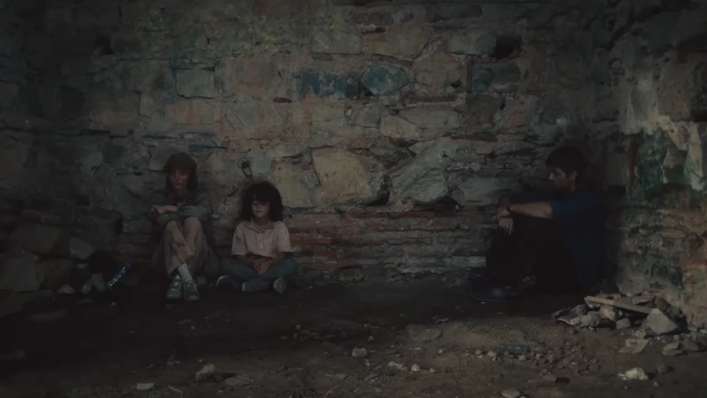 Yusuf i Nana siedzą obok siebie. Nieco dalej, w rogu, siedzi Poyraz.