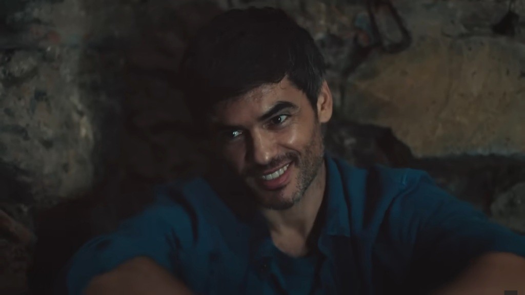 Poyraz uśmiecha się, pokazując zęby.