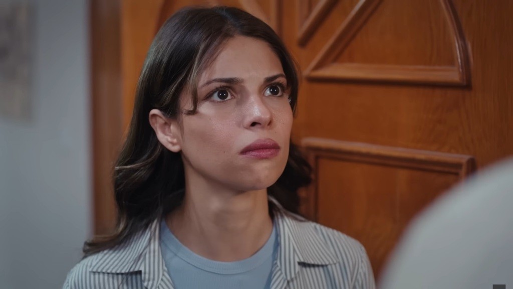 Ayse patrzy groźnie, stojąc przy drzwiach.