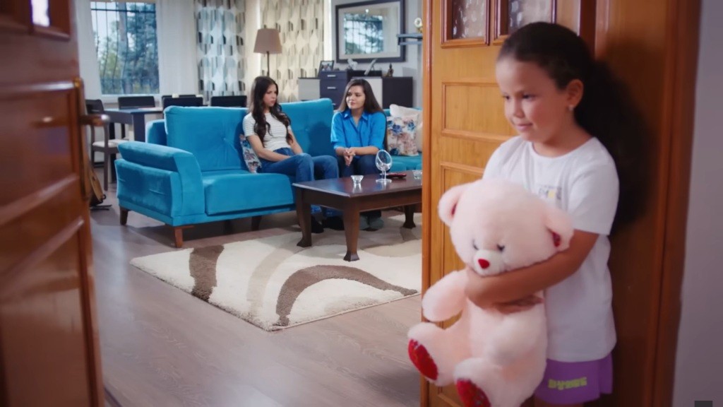 Doga podsłuchuje rozmowę swojej mamy i cioci. W rękach trzyma swojego ukochanego pluszaka.