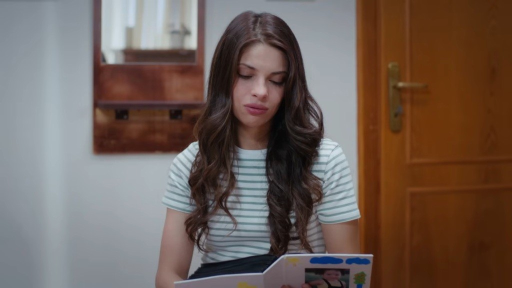 Ayse trzyma w rękach album ze zdjęciami Dogi.