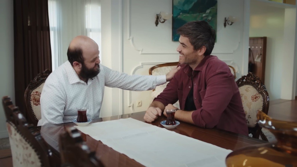 Sahin trzyma rękę na ramieniu Poyraza, który się uśmiecha.