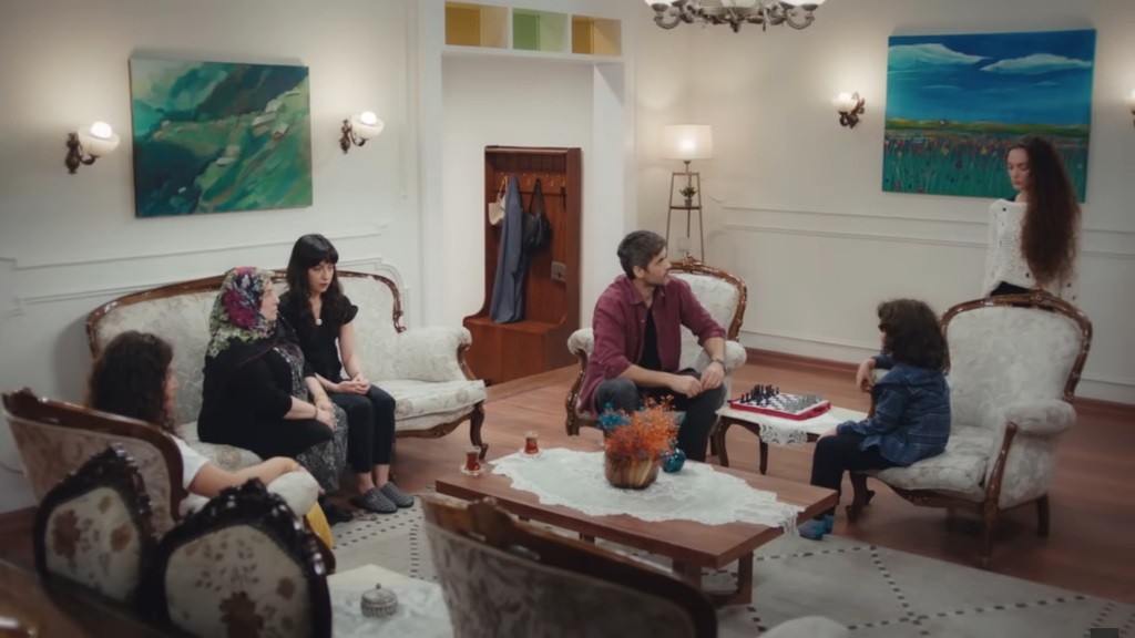 Scena w salonie. Poyraz jest zauroczony Naną w czystych ubraniach. Nie może oderwać od niej oczu.