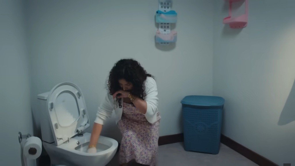 Cansel pochyla się nad toaletą.