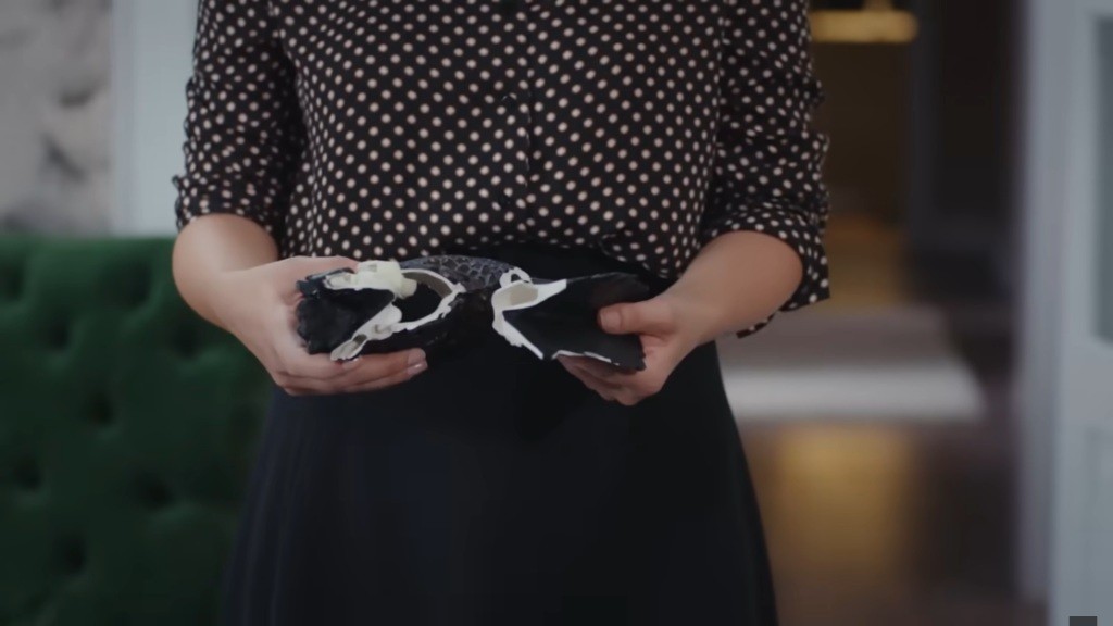 Aynur trzyma w rękach odłamki porcelanowej figurki pawia.