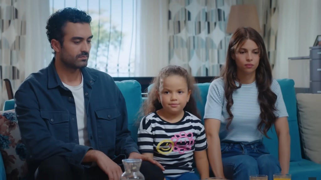 Ferit, Doga i Ayse siedzą na kanapie.