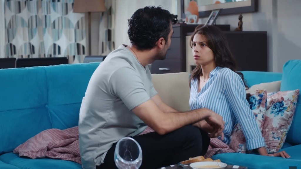 Ferit siedzi obok Ayse na kanapie.