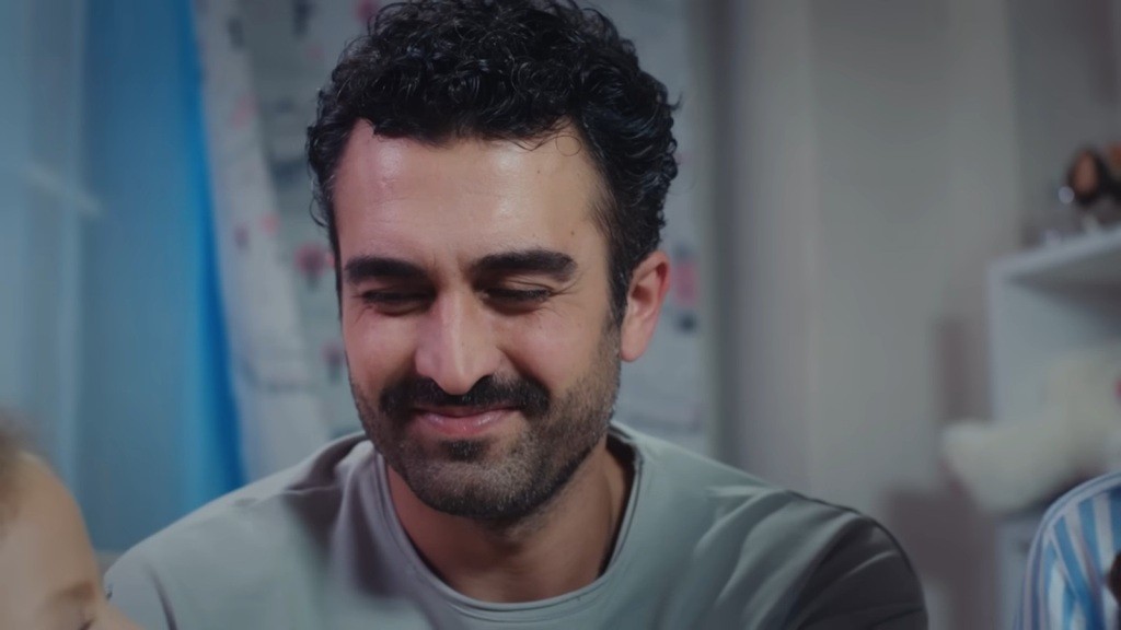 Ferit uśmiecha się, patrząc na córkę.