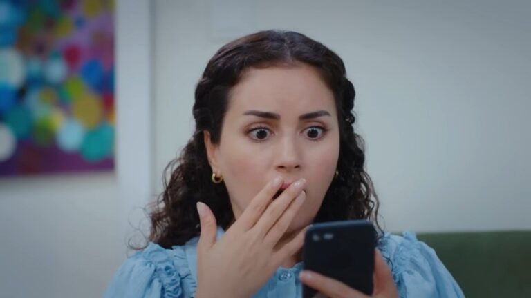 Aynur jest zszokowana, patrząc na telefon. Zakrywa usta dłonią.