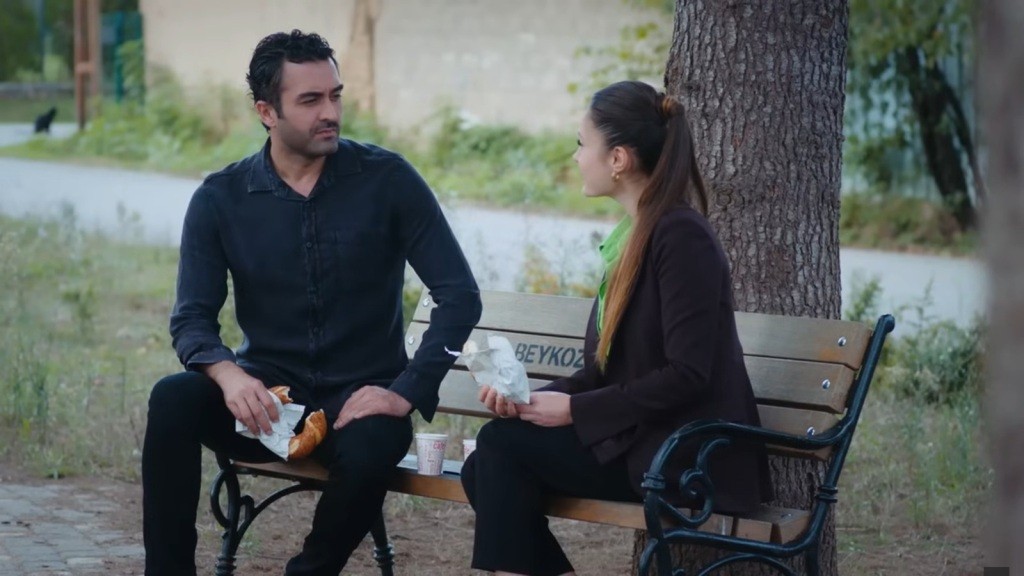 Ferit i Derya siedzą na ławce w parku.