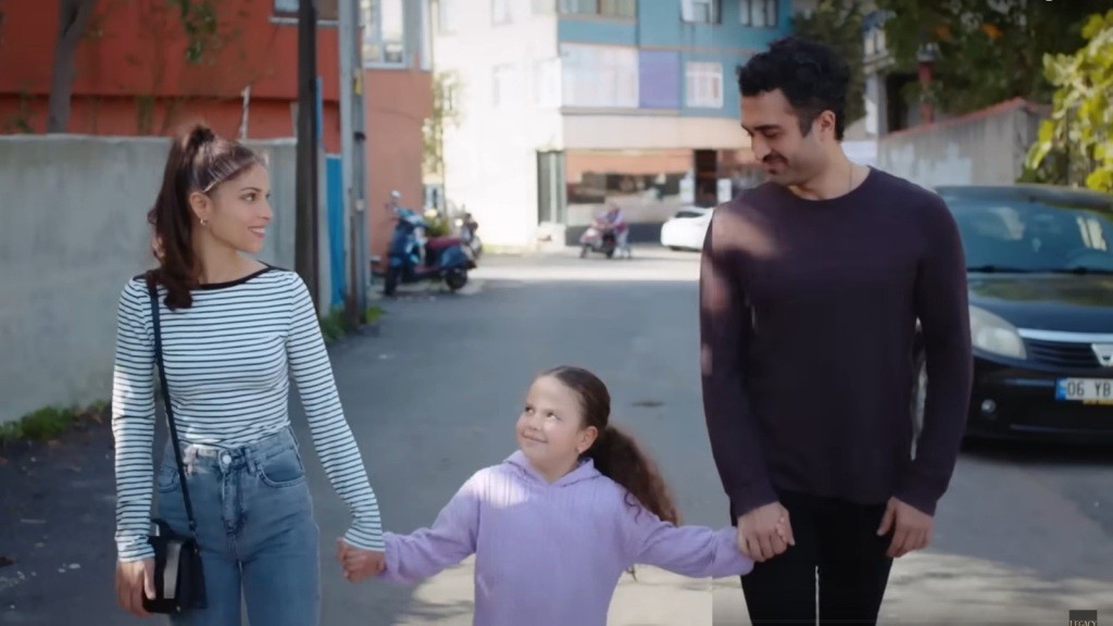 Doga idzie ze swoimi rodzicami, trzymając ich za ręce.