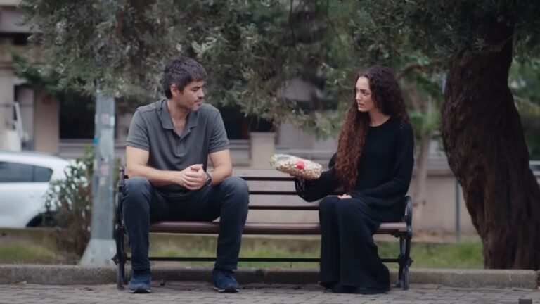 Poyraz i Nana siedzą na ławce. Dziewczyna wyciąga w jego stronę paczkę fistaszków.