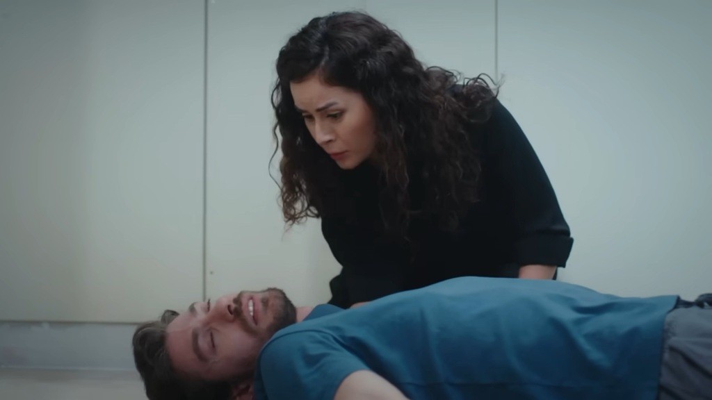 Aynur pochyla się nad Sinanem i próbuje go ocucić.